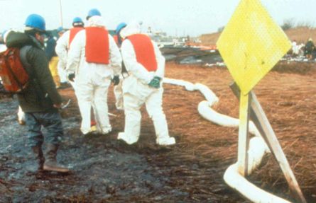 Workers putting out boom on a beach area. 