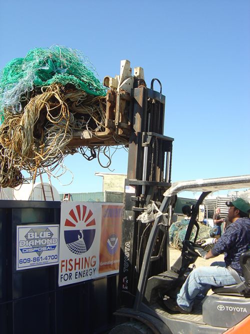 Forklift truck loading nets into a disposal bin.