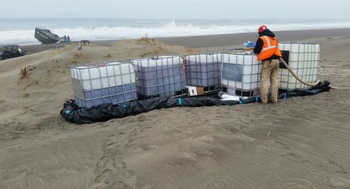 Fuel containers lined up on a beach.