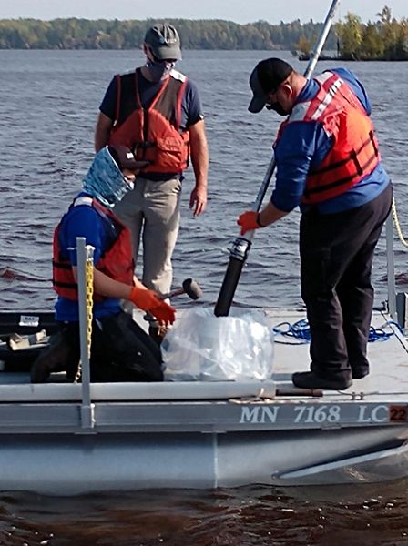 Three people working on a boat in the water.