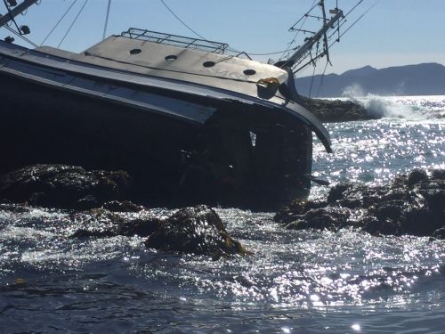 Grounded vessel on its side on a beach.