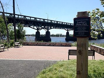 Park next to a river; bridge in background.