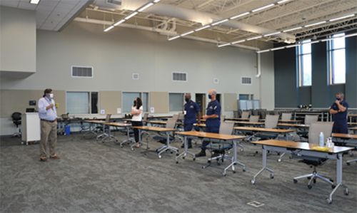 Man speaking to several people in a large meeting room.