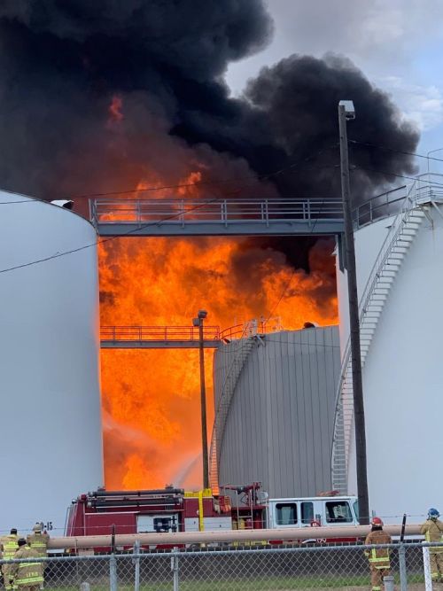 Fire visible between tanks in a tank farm.