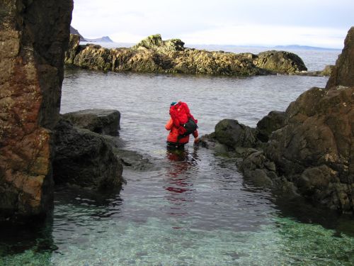 Person sampling in water between two boulders.