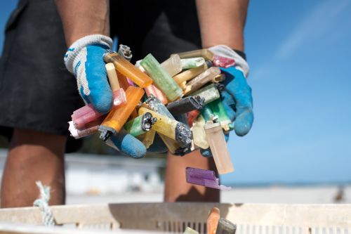 Hands holding a pile of discarded lighters.