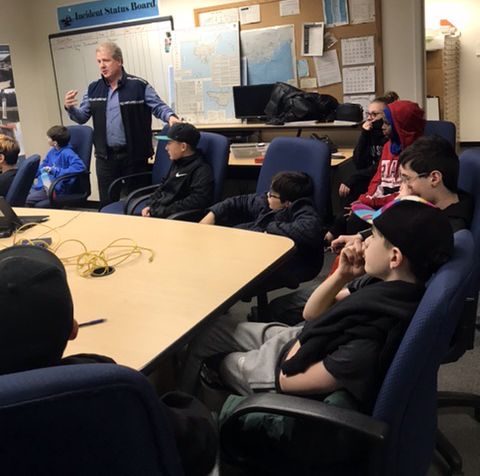 Man speaking to children seated at a table.