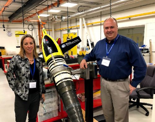 Two people posing next to large underwater glider.