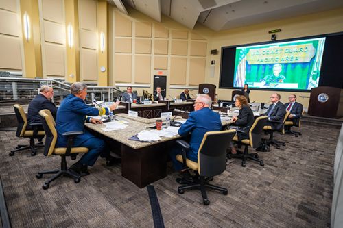 Group of people assembled around a large conference table. 