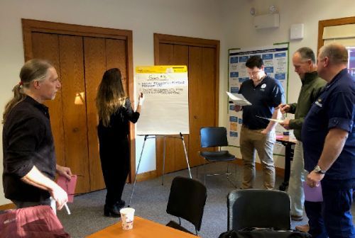 People standing, reading and writing on a large post-it.