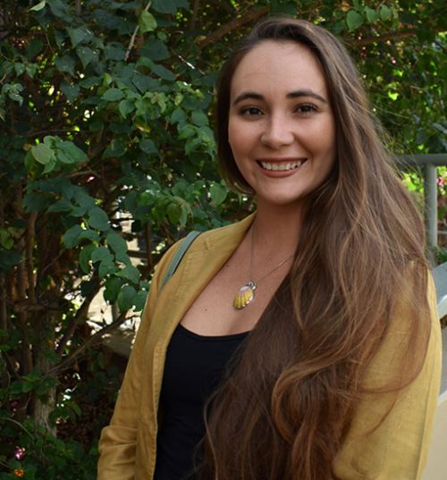 A woman outdoors in a yellow sweater.