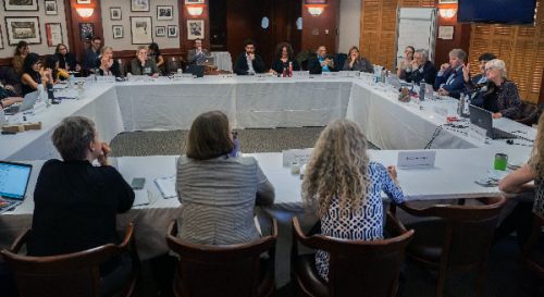 Large group sitting at tables arranged in a square.