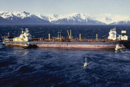 A vessel in water with snowy mountains in the background.