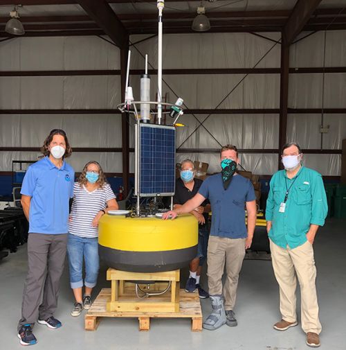 Four people standing around a large piece of equipment. 