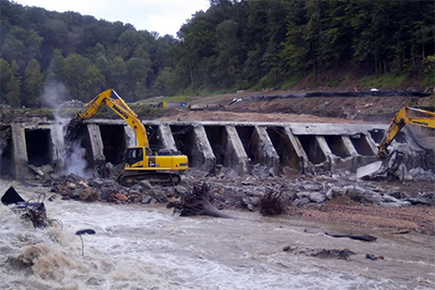 Heavy equipment being operated at the site of an old dam.