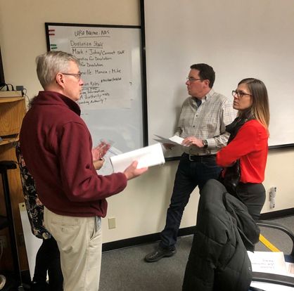 Three people standing near a whiteboard talking. 