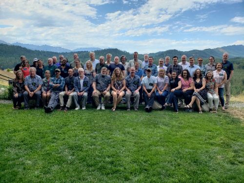 Large group of people pose for photo on a lawn.