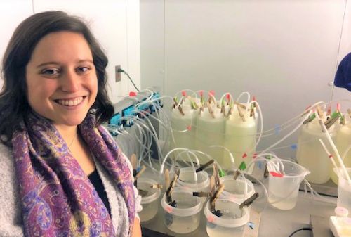 Woman posing in front of a table with science equipment.