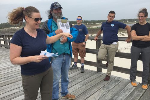 A group of people on a pier on a beach.