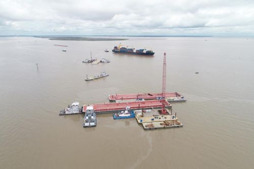 An aerial view of three barges with several vessels around them. 