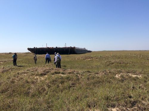 Barge in a field with bystanders looking on.