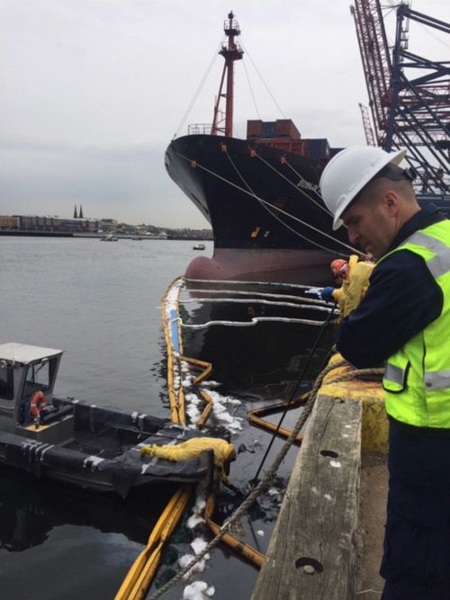 Workers on boats attempt to contain oil spilled into the water. 
