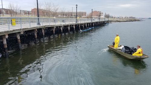 Workers view spilled oil from a boat. 