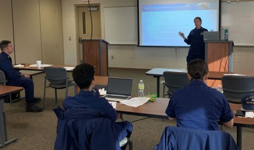 A person at a podium presenting to a group of people.