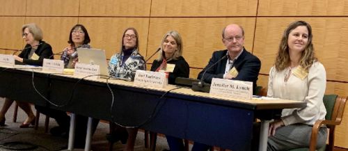 Six people seated on one side of a table.