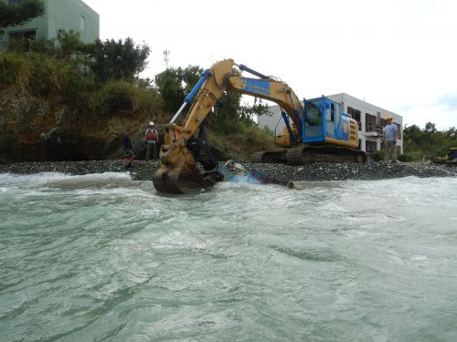 Crane pulling boat parts from the water.