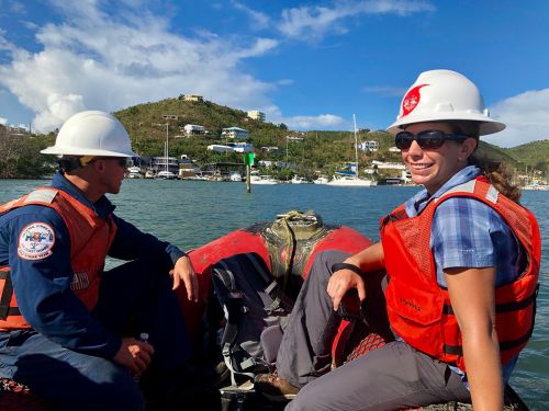 Man and a woman in a boat with water and hills in background.