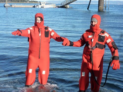 Two people in orange jump suits wading through water. 