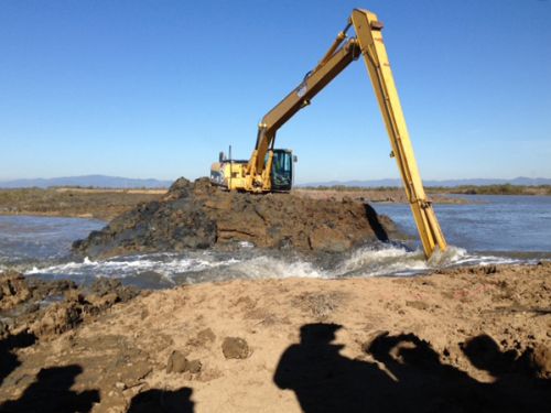 Heavy equipment digging at a levee.