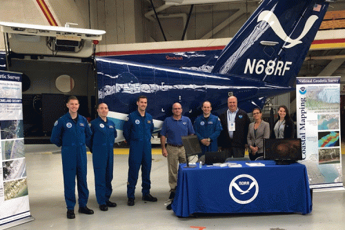 A group of people pose for a photo in front of an aircraft.