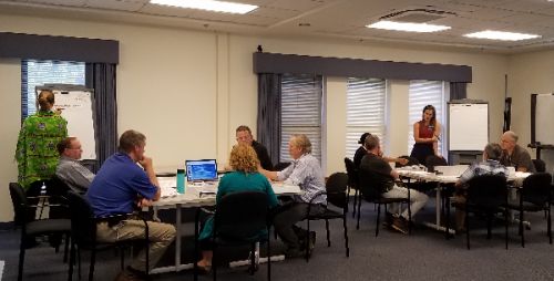 People sitting at tables with flip charts in the room.