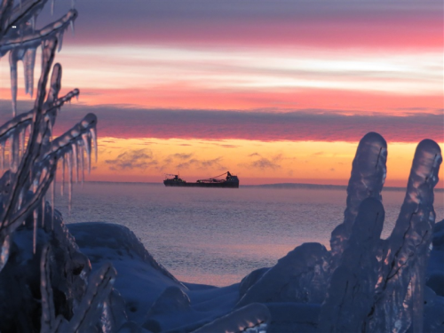 A vessel on a horizon with a sunset in the background.