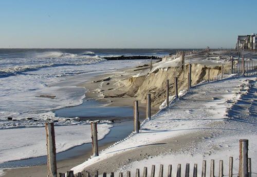 Snow on beach; fences along beach.