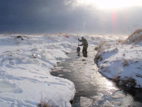 Two people sampling in a stream after the Adak oil spill.