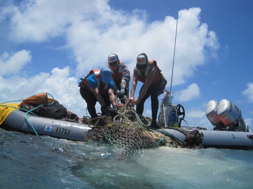 Image of scientists pulling discarded nets onto their boat.