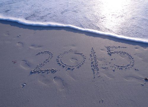 2015 written on a sandy beach with an approaching wave.