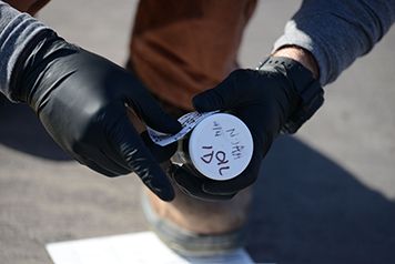 Two hands place a label on a jar of oil.