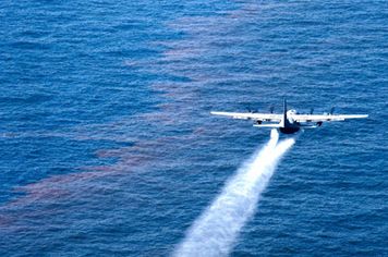 An airplane applies dispersant to an oil spill.