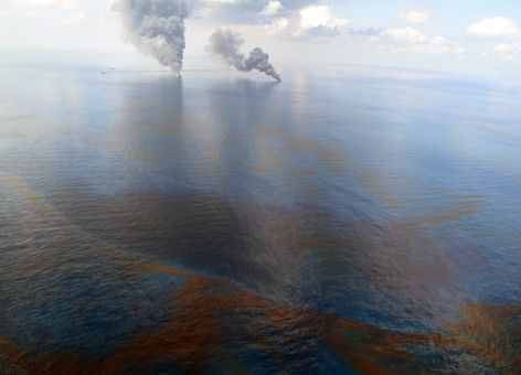 Oil on the ocean and smoke visible in the distance.