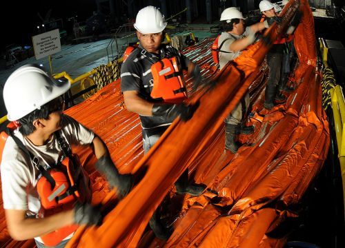 Response workers load oil containment boom onto a supply ship in Louisiana.