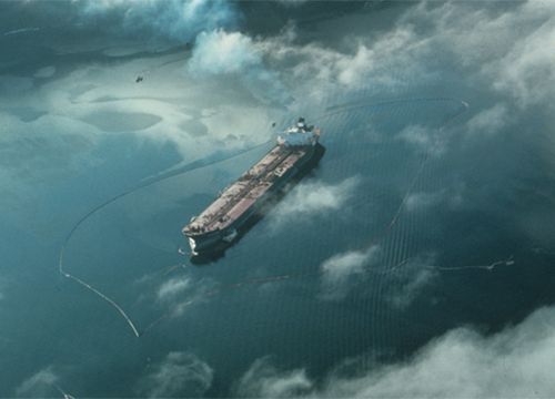 Aerial view of Exxon Valdez tanker with boom and oil on water. 