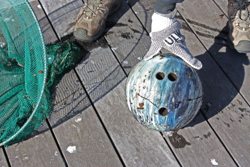 A cracked bowling ball with a net used to scoop it out of a river.