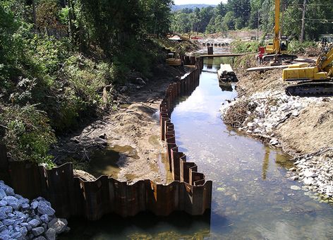 Heavy machinery removes soil and rocks in a polluted stream.