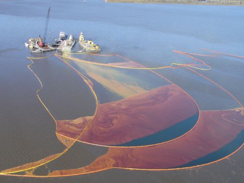 An aerial view of varying shades of oil being collected in pollution boom from a well blowout.