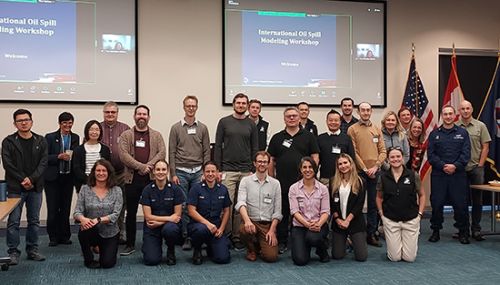 A group of spill modeling scientists stand together in a group photo in a conference room setting.