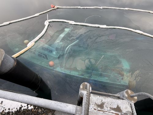 A sunken vessel with observed sheen in the surrounding water in a small boat harbor in Adak, Alaska.